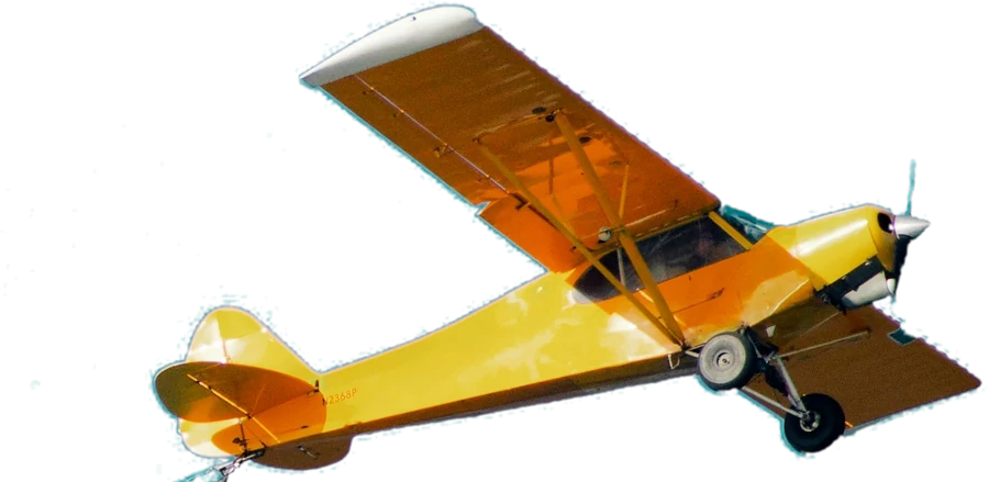 A yellow single-engine aeroplane towing a banner line across a clear blue sky.